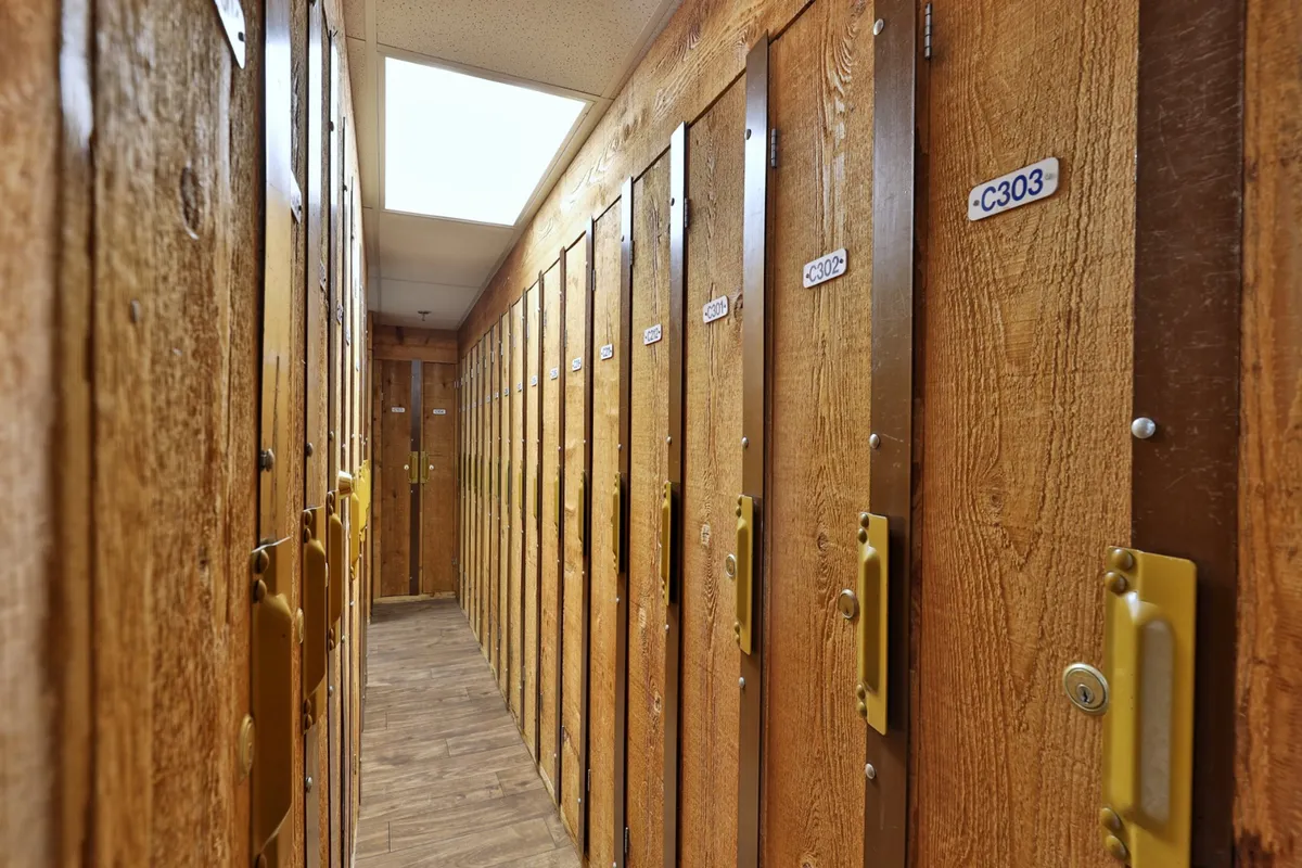 A row of wooden lockers with golden handles and numbered labels, suggesting organized and secure storage for personal belongings in a shared amenity space—likely part of a gym, pool, or sports center.