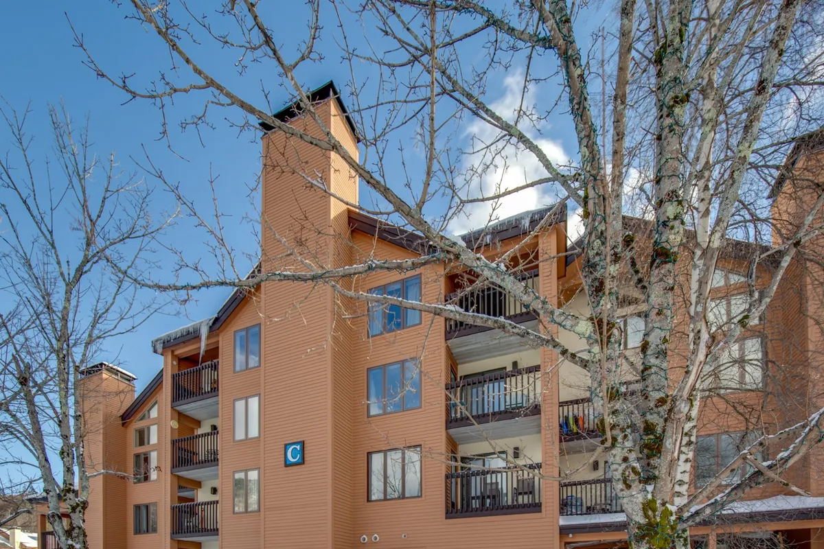 A view of the building’s structure with balconies overlooking a tree-lined area. The balconies suggest opportunities for enjoying fresh air, watching sunsets, or socializing after a day of adventure. The setting is both residential and connected to nature.