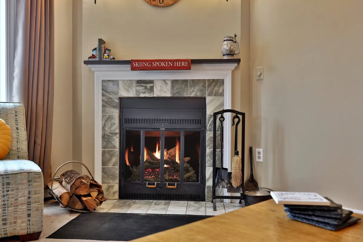A cozy community lounge area featuring a welcoming fireplace, comfortable seating, and subtle signage. Guests are gathered around the fire, reading and engaging in friendly conversation, evoking a sense of warmth and togetherness.